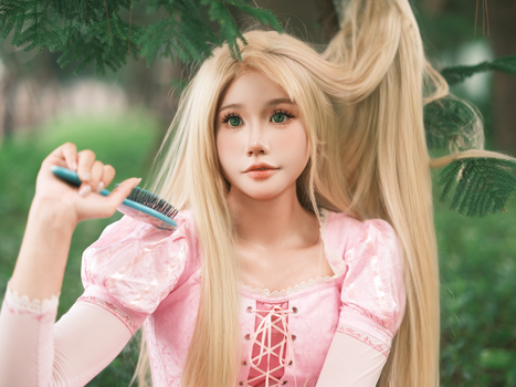 A woman in cosplay with long blonde hair and pink dress brushes her hair in an outdoor setting.