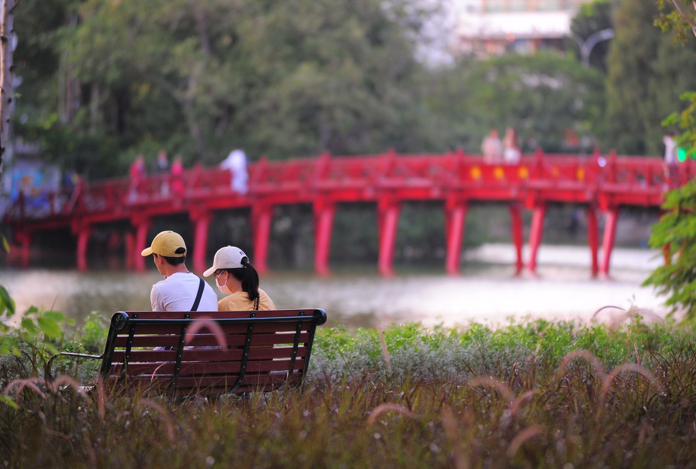 Serene Moment on Bench by Red Wooden Bridge · Free Stock Photo