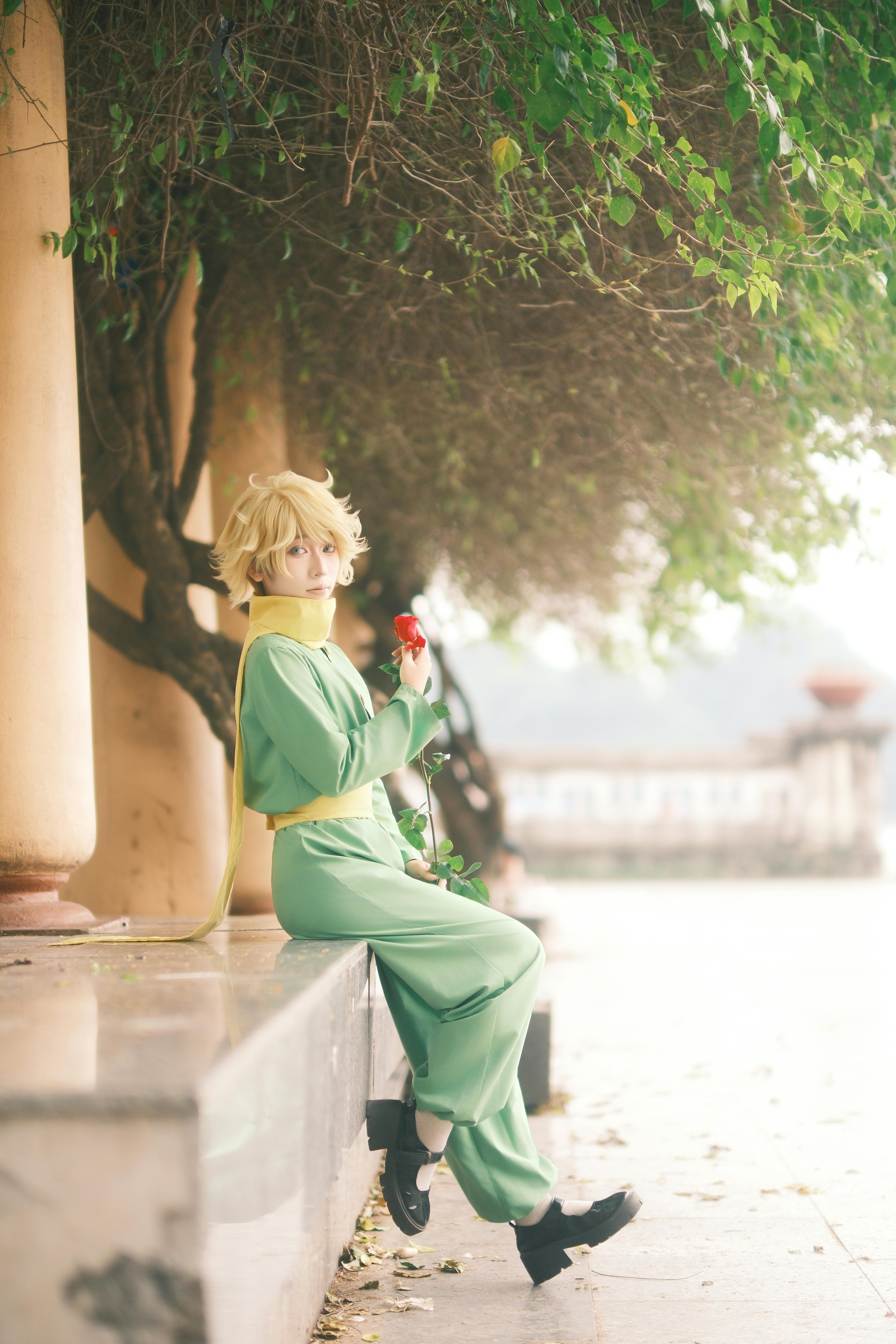 Person in cosplay attire sitting under lush trees, creating a serene and magical ambiance.