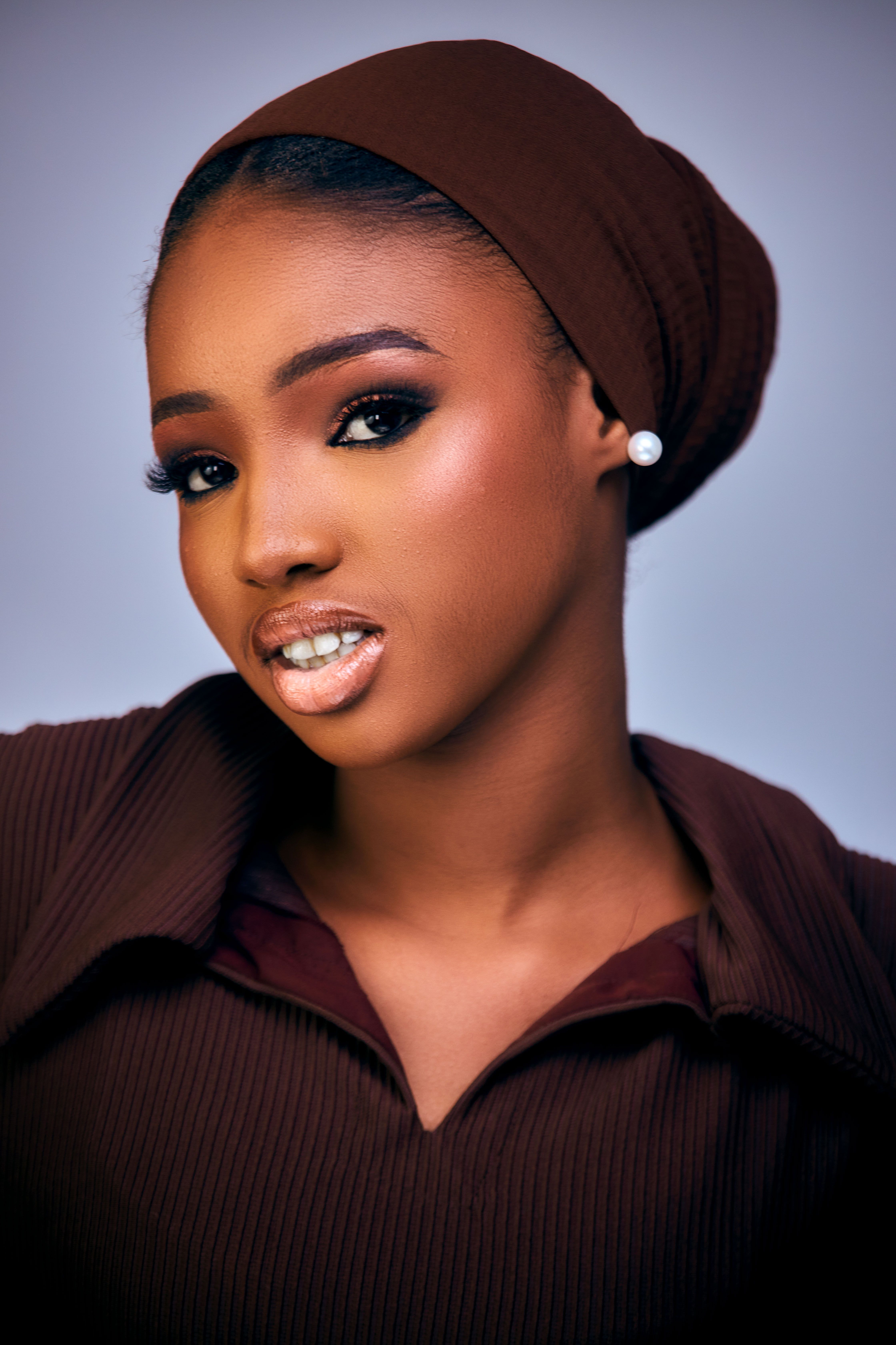 Portrait of a stylish woman with elegant makeup and brown attire.