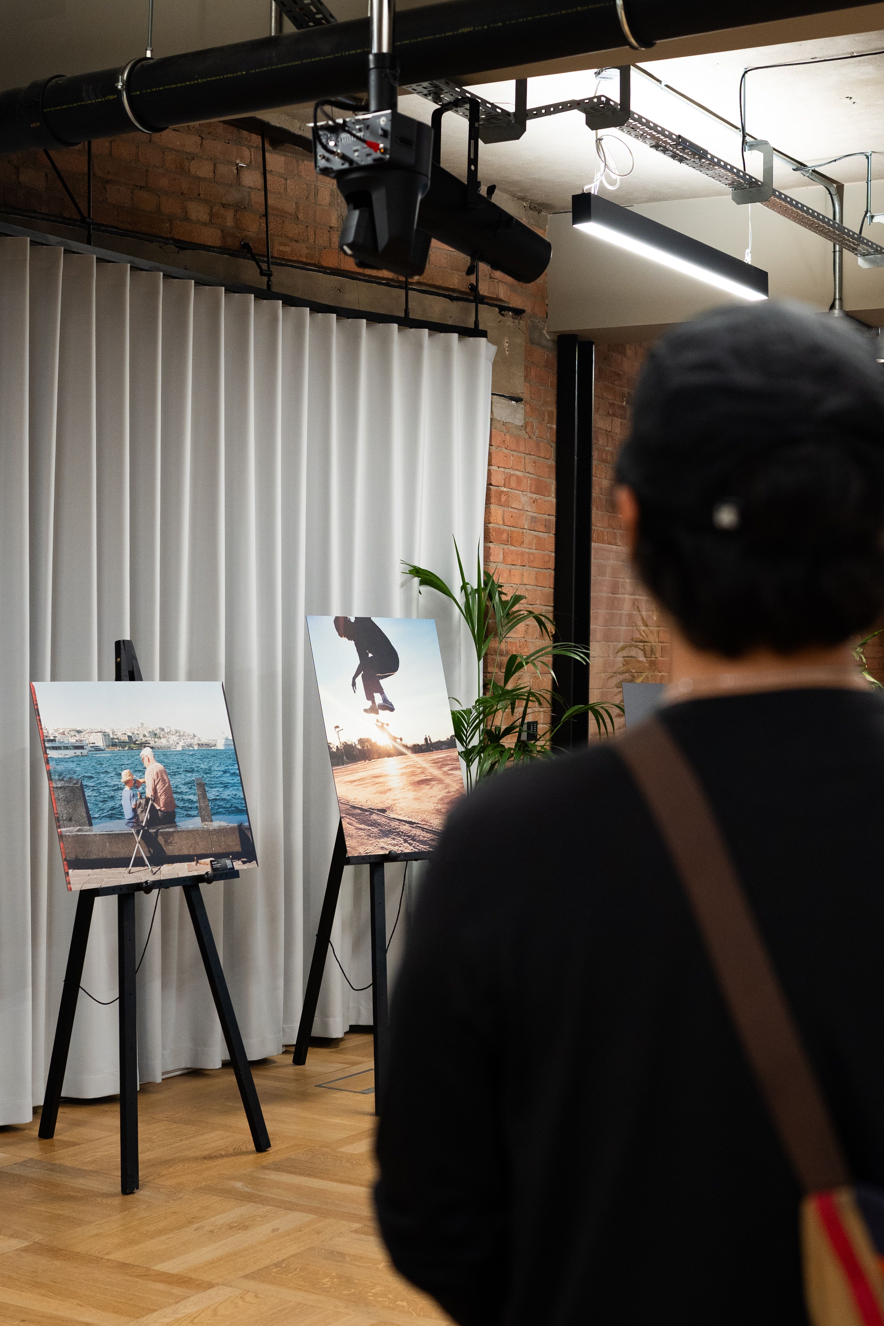 A visitor admires two framed photographs in a modern indoor gallery setting.