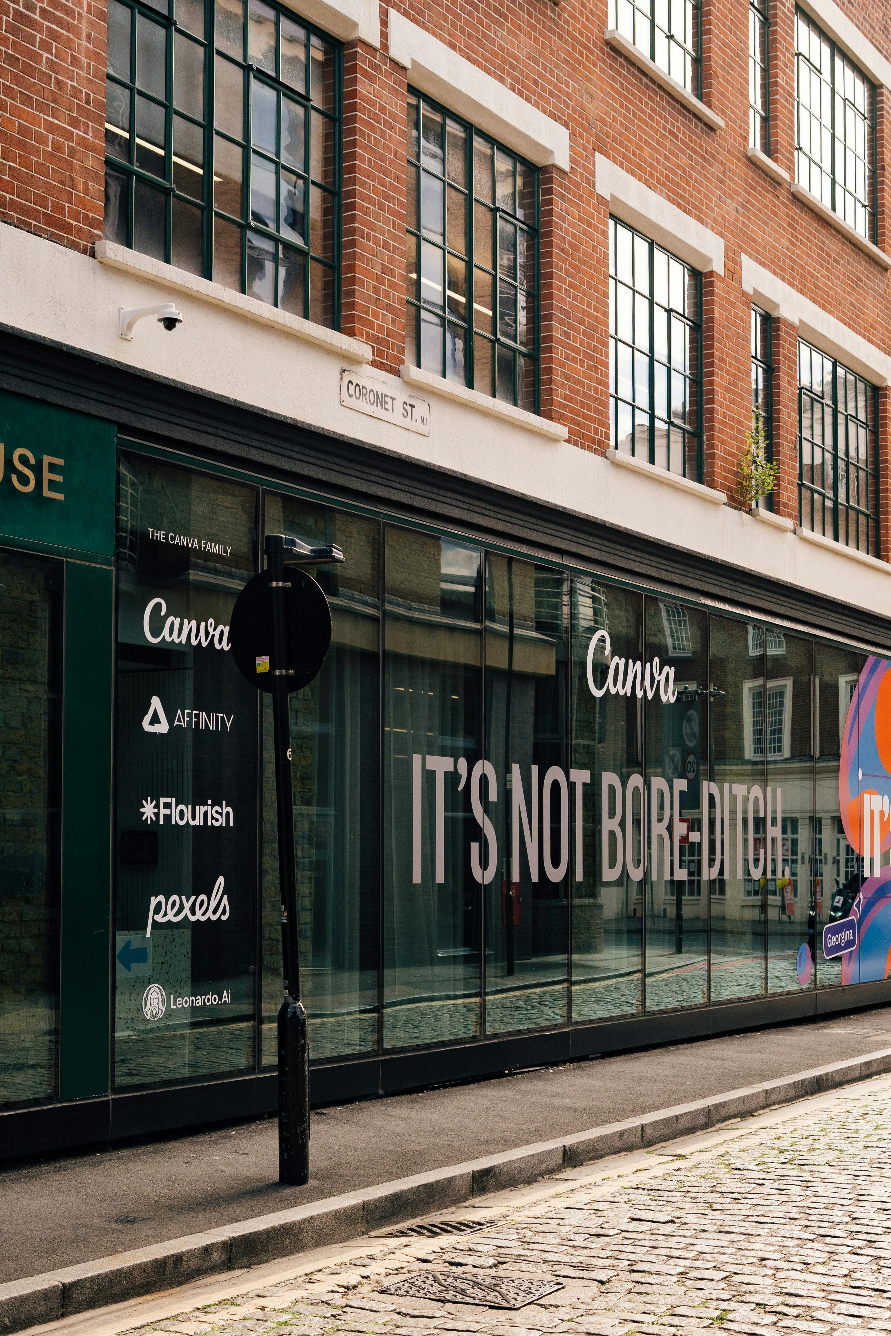 Street view of a brick building in London with a prominent Canva advertisement.