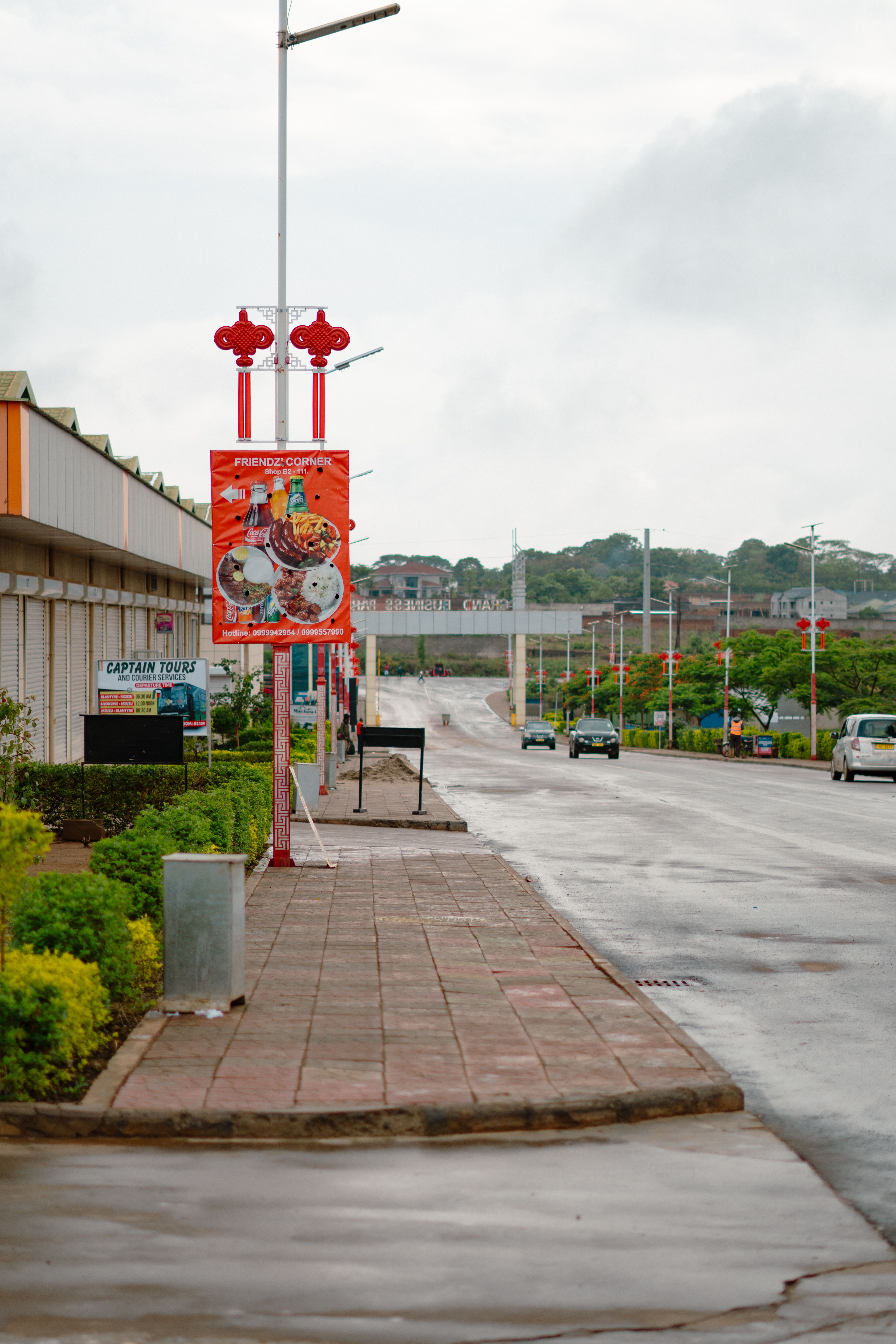 A wet street scene in Lilongwe, Malawi, showcasing vibrant signage and urban architecture.
