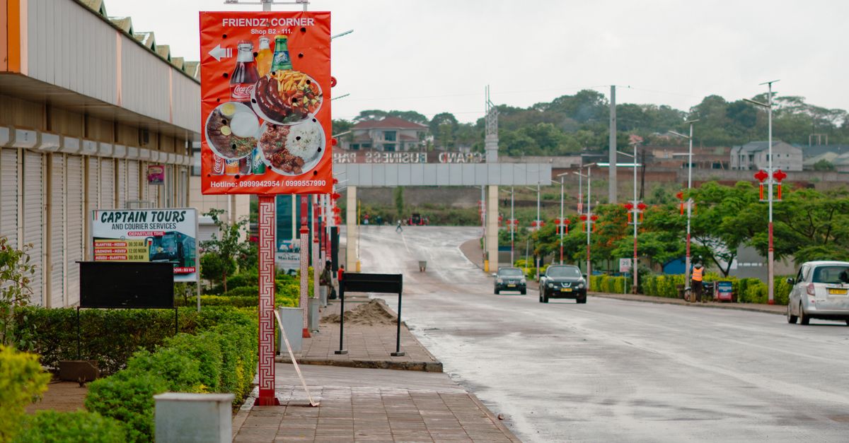 A wet street scene in Lilongwe, Malawi, showcasing vibrant signage and urban architecture.