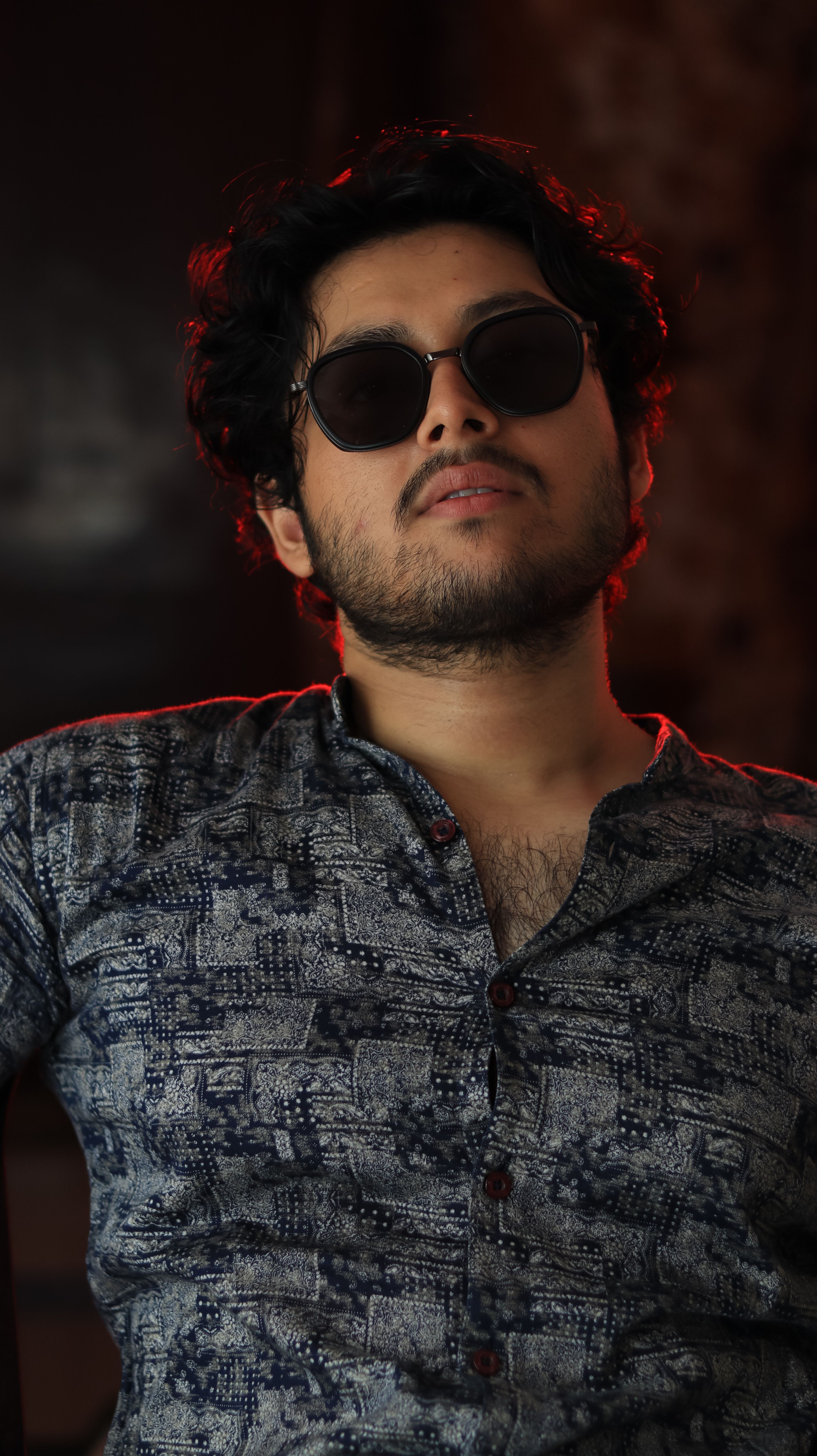Portrait of a stylish man with sunglasses, exuding a cool attitude, shot indoors.