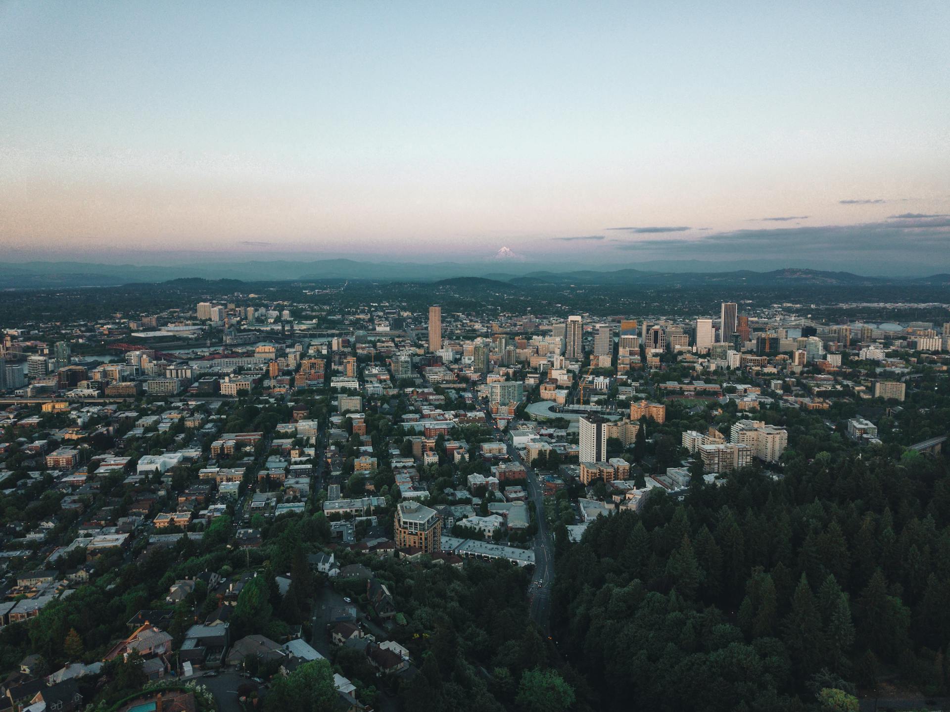 Aerial view of Portland cityscape during sunset, showcasing urban landscape and lush surroundings.
