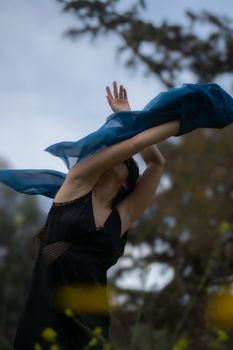 Woman dancing outdoors with flowing fabric creating a dynamic motion blur effect.