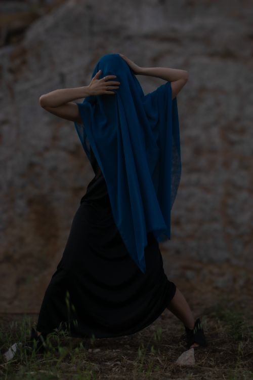 Free A person draped in a blue veil poses against a rustic outdoor background, exuding mystery. Stock Photo