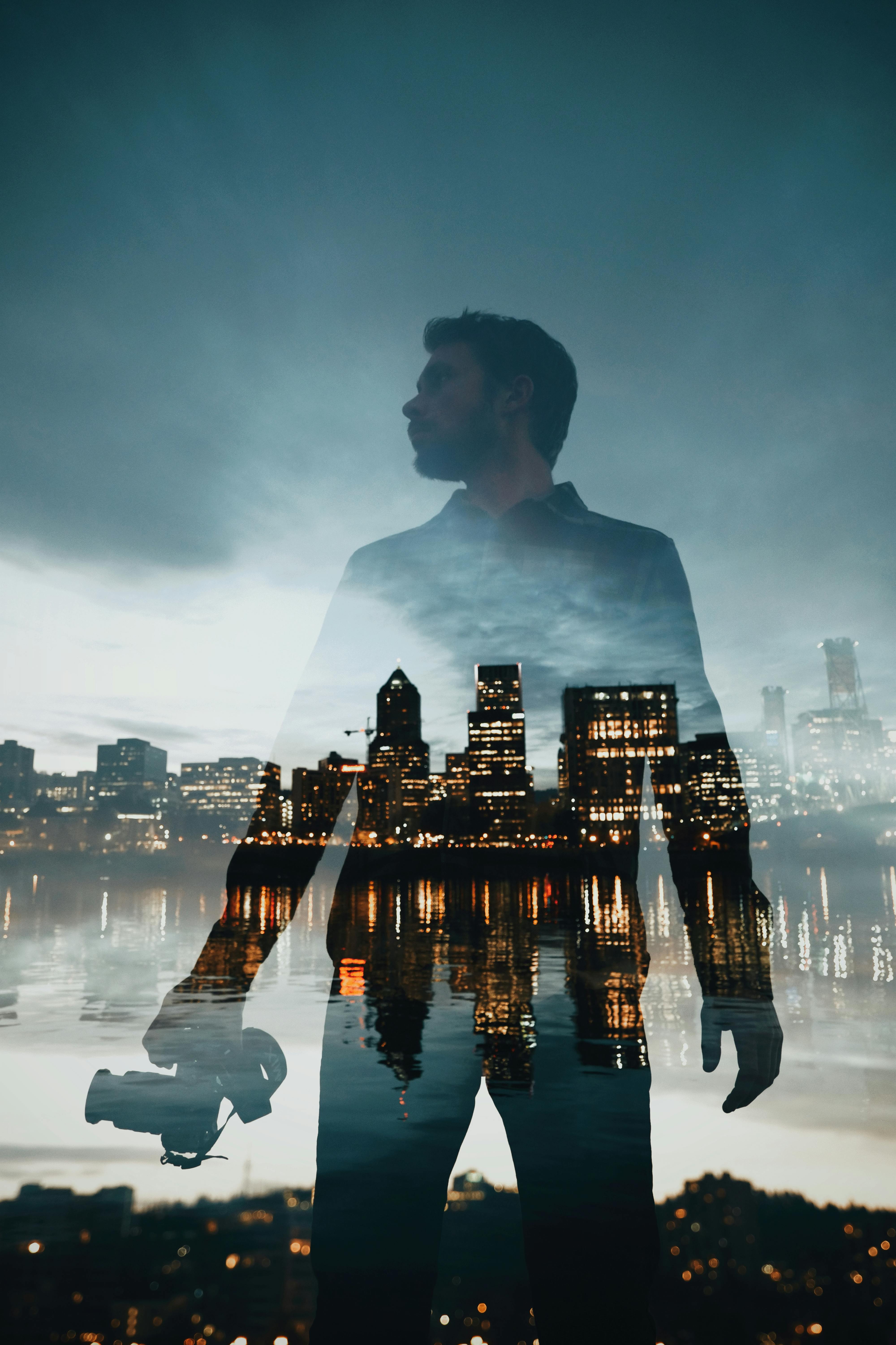 male photographer on shore against glowing cityscape