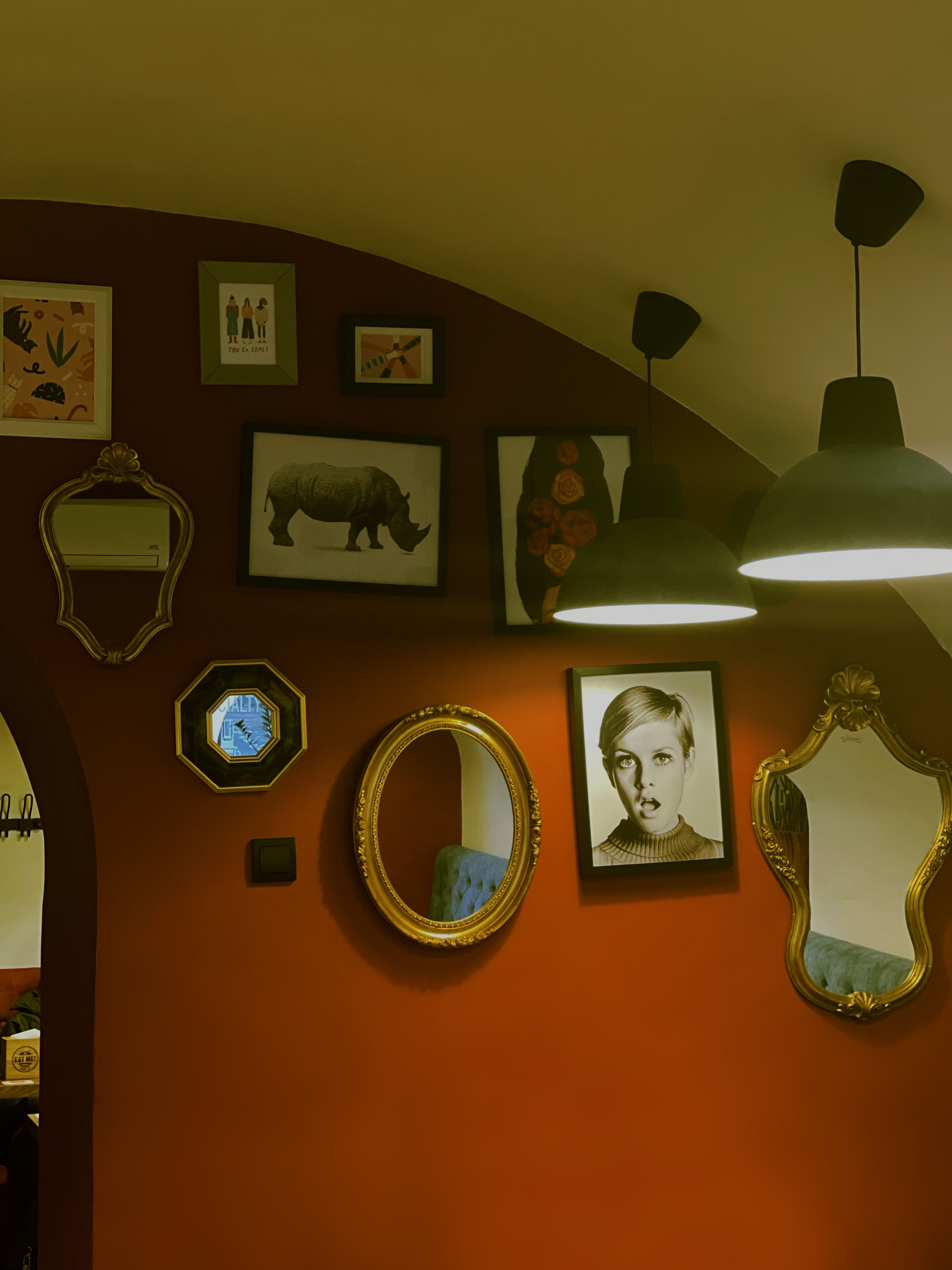 Warm ambiance with vintage mirrors and eclectic artwork in a boutique cafe.