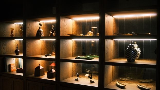 Wooden display shelves with artistic ceramics and sculptures elegantly lit for a warm ambiance.