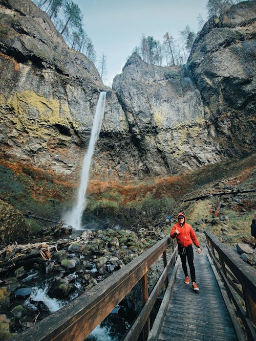 Tourist on bridge in ravine with waterfall