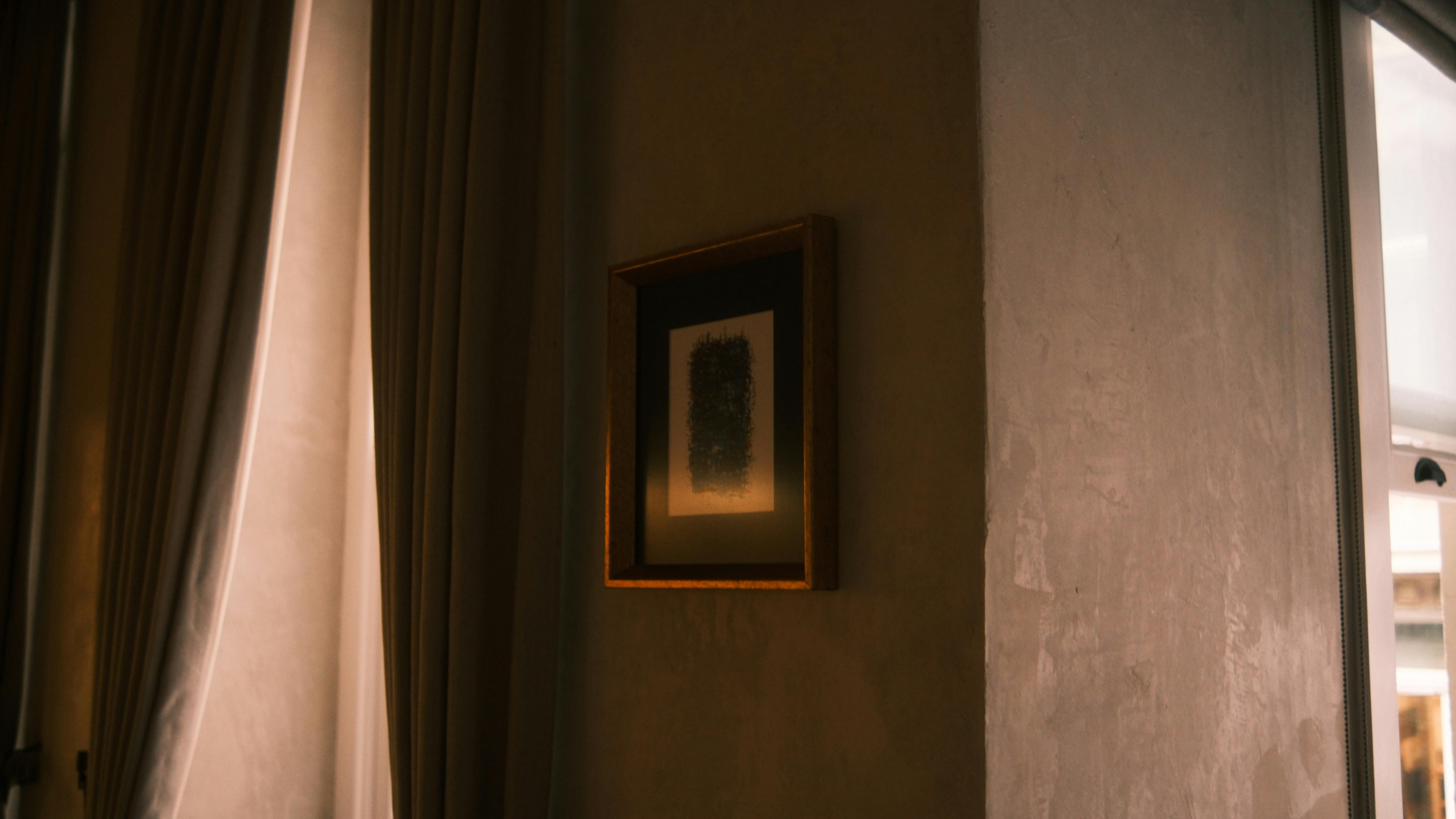 Gratuit Une pièce à l'éclairage tamisé, ornée d'une œuvre d'art encadrée sur un mur texturé. Photos