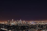 从洛杉矶上空俯瞰，夜幕下的现代摩天大楼在星空中熠熠生辉，景象令人惊叹