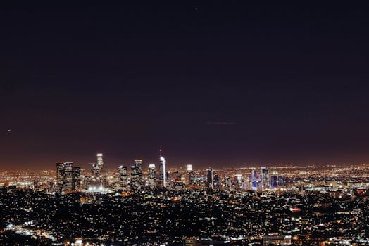 从洛杉矶上空俯瞰，夜幕下的现代摩天大楼在星空中熠熠生辉，景象令人惊叹