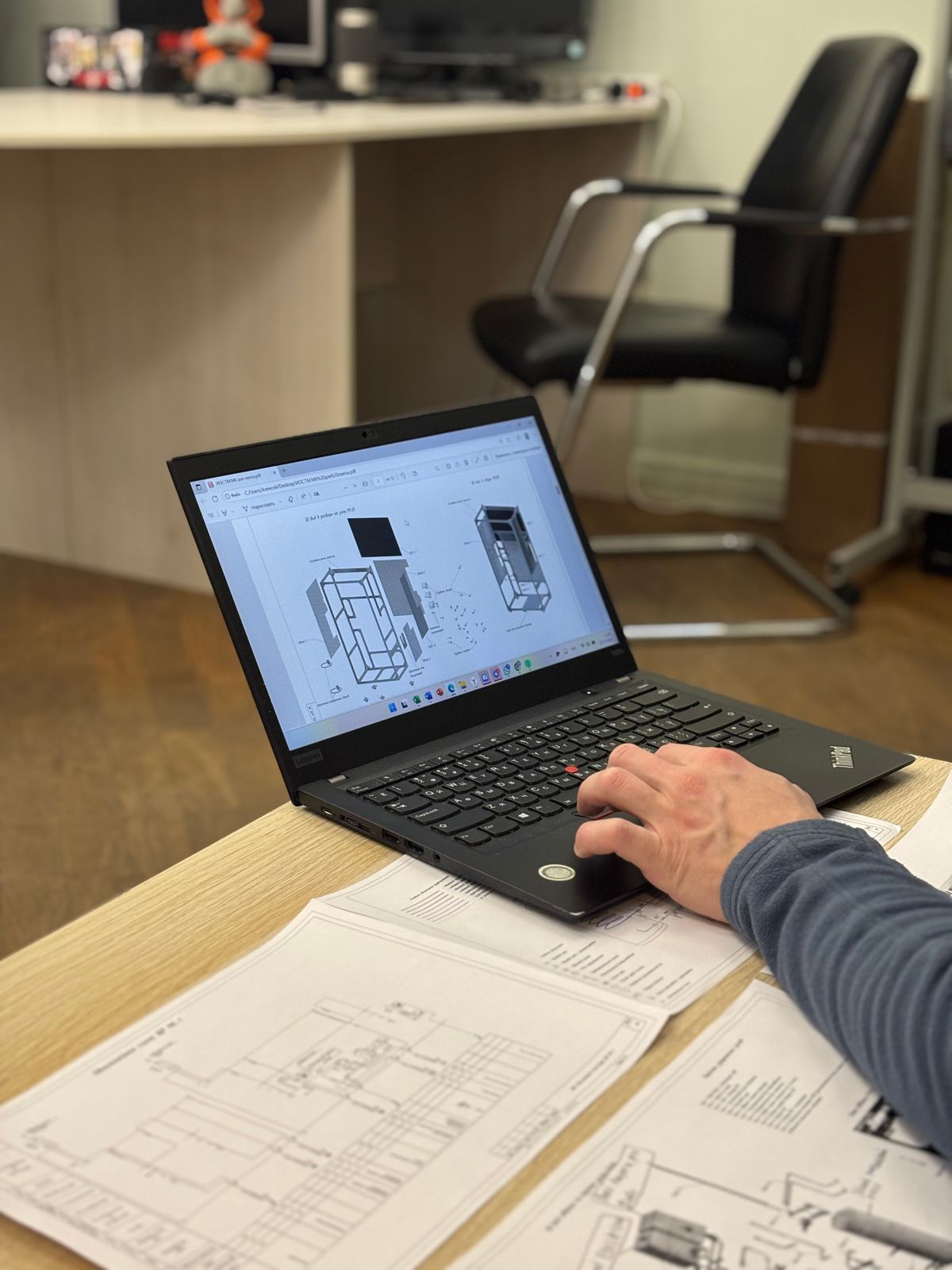 Design engineer reviewing technical blueprints on a laptop at a desk