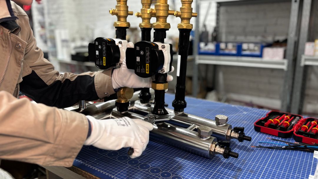 A technician assembling the pipework and controls on a water heating unit