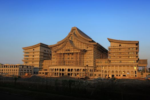 Expansive building under construction during sunset with scaffolding.