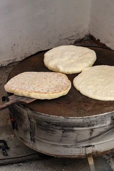 Close-up of traditional flatbreads baking on a tandoor oven in an indoor setting.