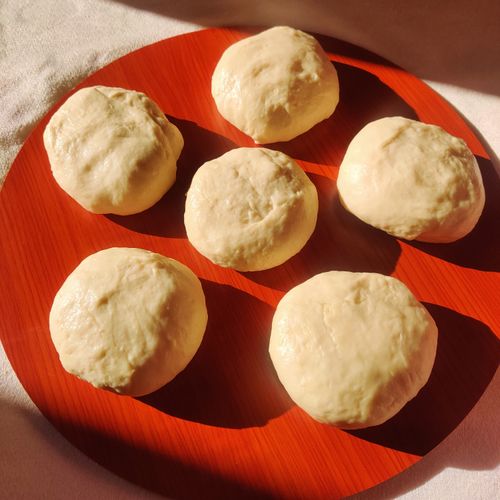 Proofed dough rounds on a red tray — photo by Nour Al Huda Zardan on Pexels