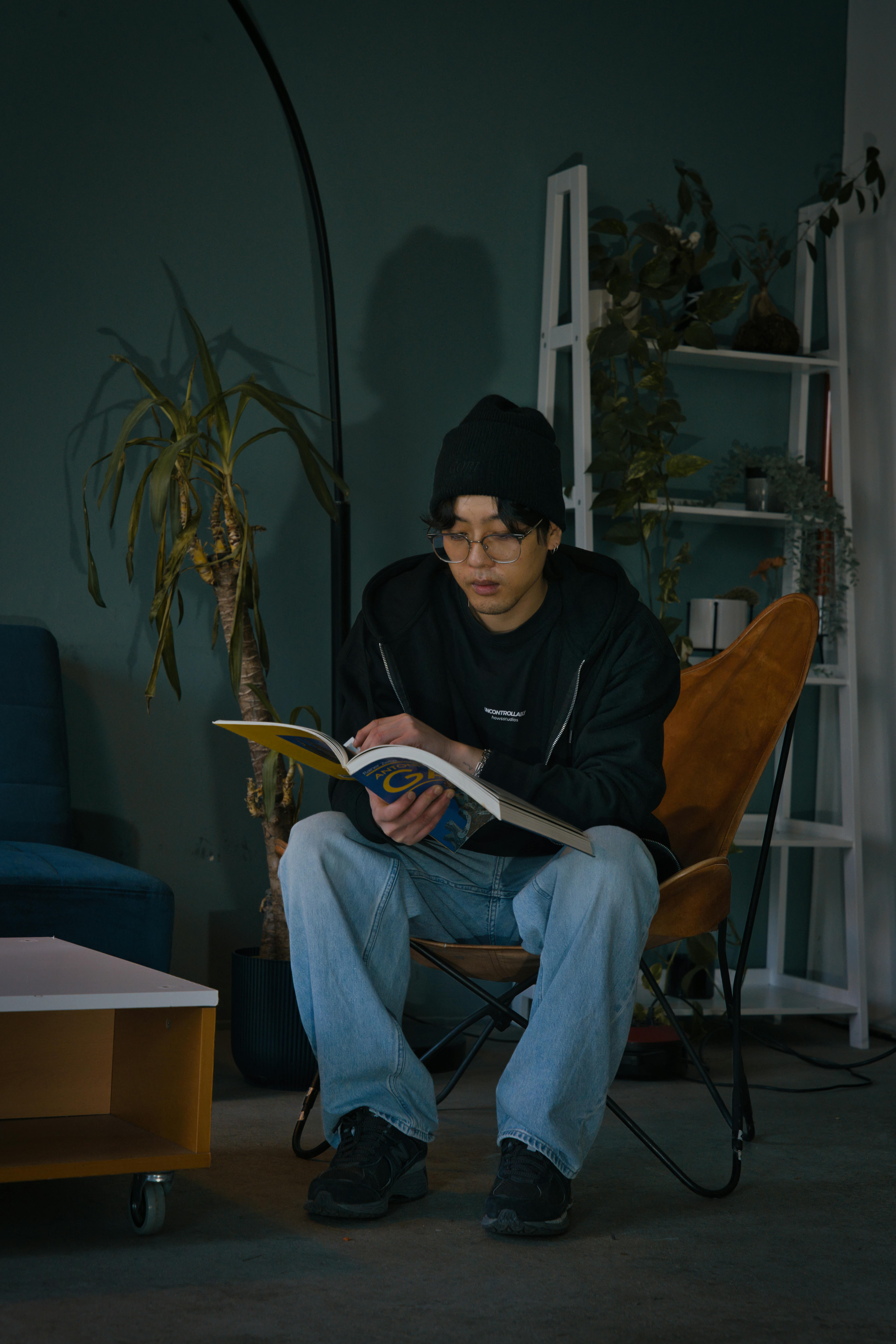 免費 一位時尚的年輕男子在柏林一間現代公寓裡讀書，周圍環繞著綠植。 圖庫相片