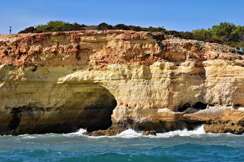 Free Rugged cliffs in Algarve, Portugal with waves crashing along the shore on a sunny day. Stock Photo