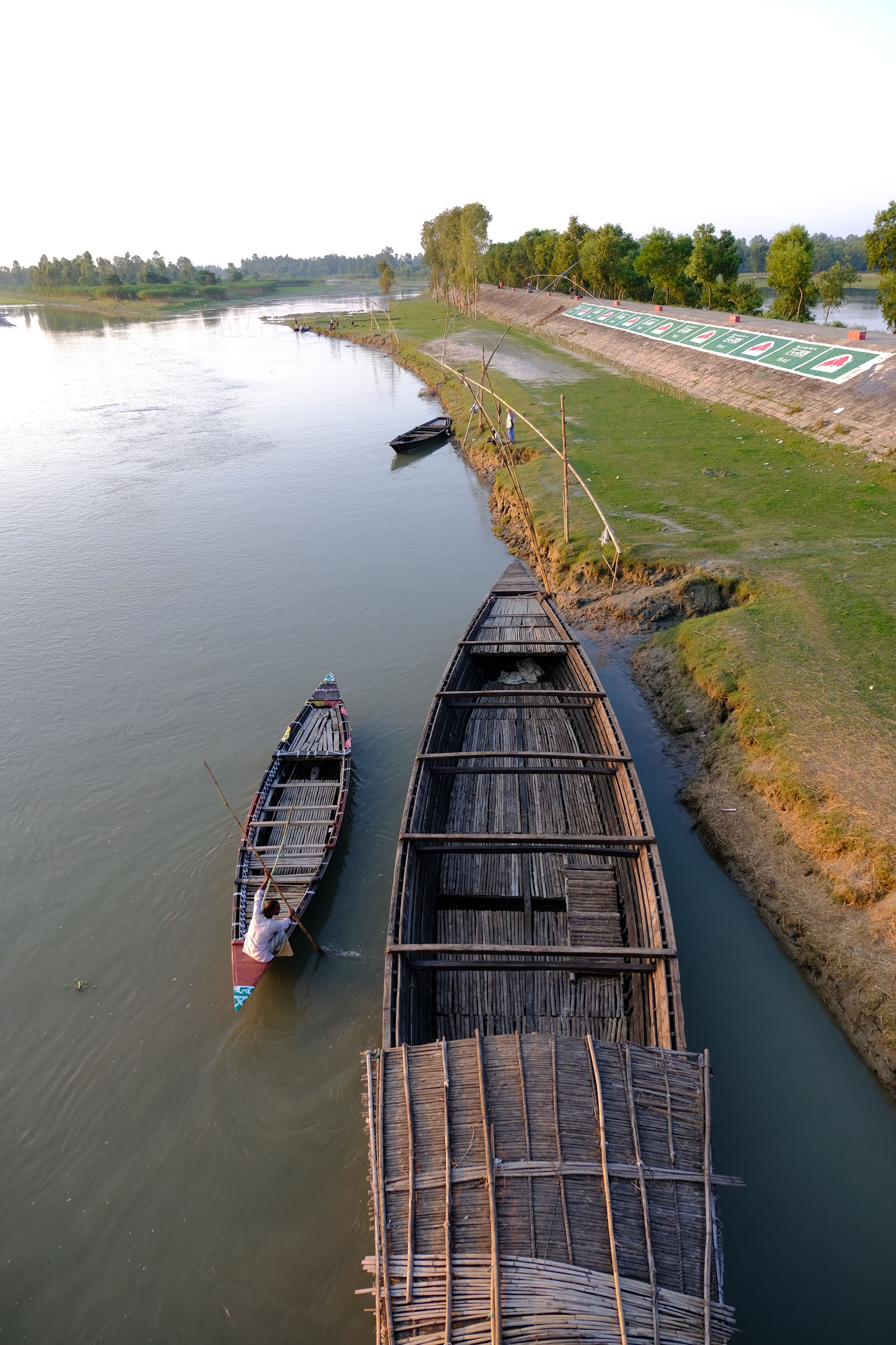 Scenic view of traditional wooden boats docked on a tranquil riverbank under a clear sky.