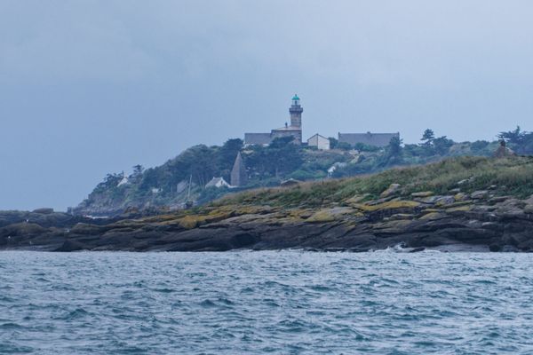 Phare de Chausey sur sa colline boisée vu depuis la mer