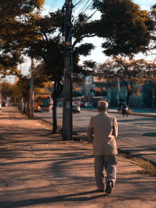 Free Elderly man in a suit walking alone on a sunny street in Brazil. Stock Photo