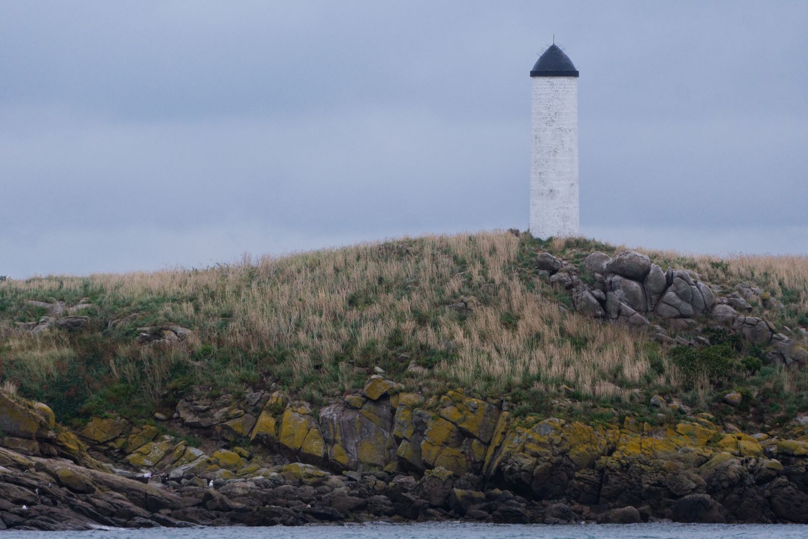 Serene view of a lighthouse on a rocky shore in Saint-Planchers, France