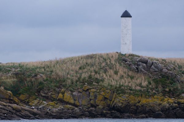Serene view of a lighthouse on a rocky shore in Saint-Planchers, France