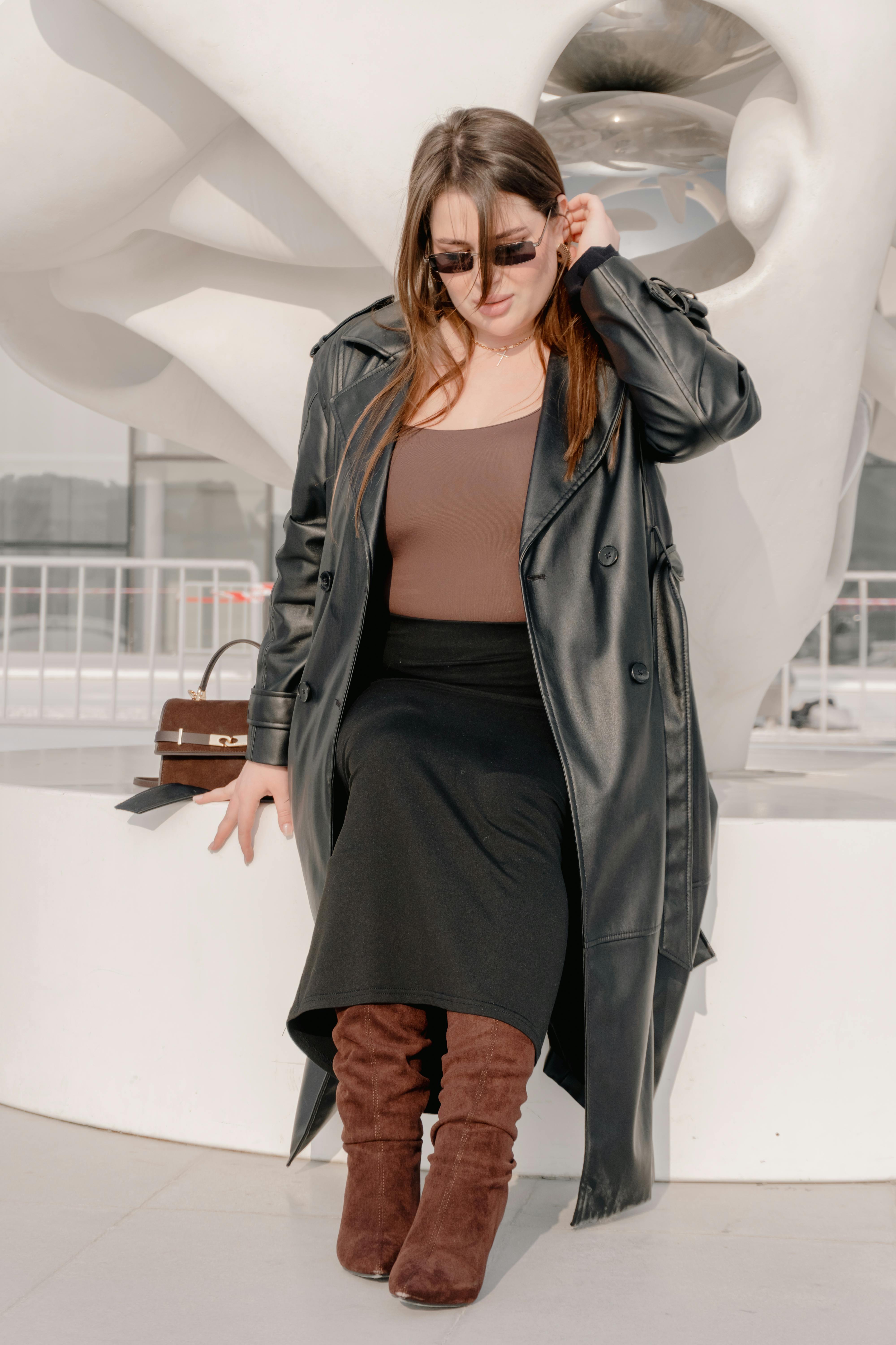 Free Stylish woman in a leather coat enjoys the sun, exuding confidence and modern elegance. Stock Photo