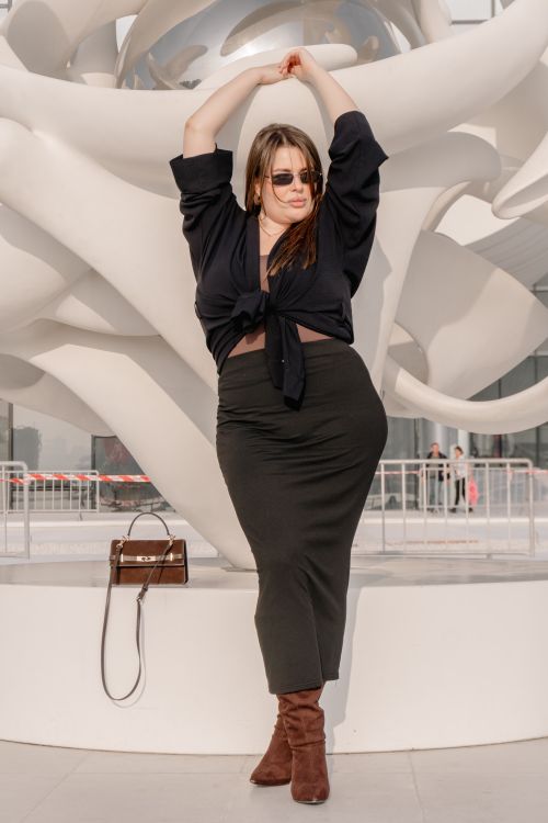 Free A fashionable woman strikes a pose in front of a contemporary outdoor sculpture. Stock Photo