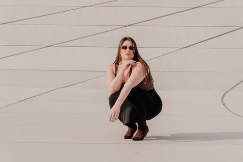 Free Stylish woman in sunglasses and boots poses against modern architectural backdrop. Stock Photo