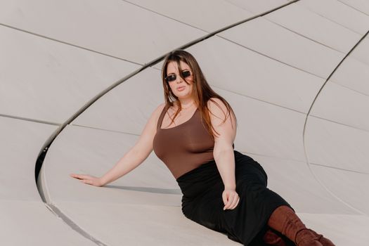 Woman in fashionable attire posing by modern architecture outdoors.