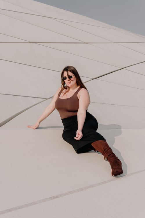 Free Fashionable woman in sunglasses posing elegantly on modern architectural structure in daylight. Stock Photo