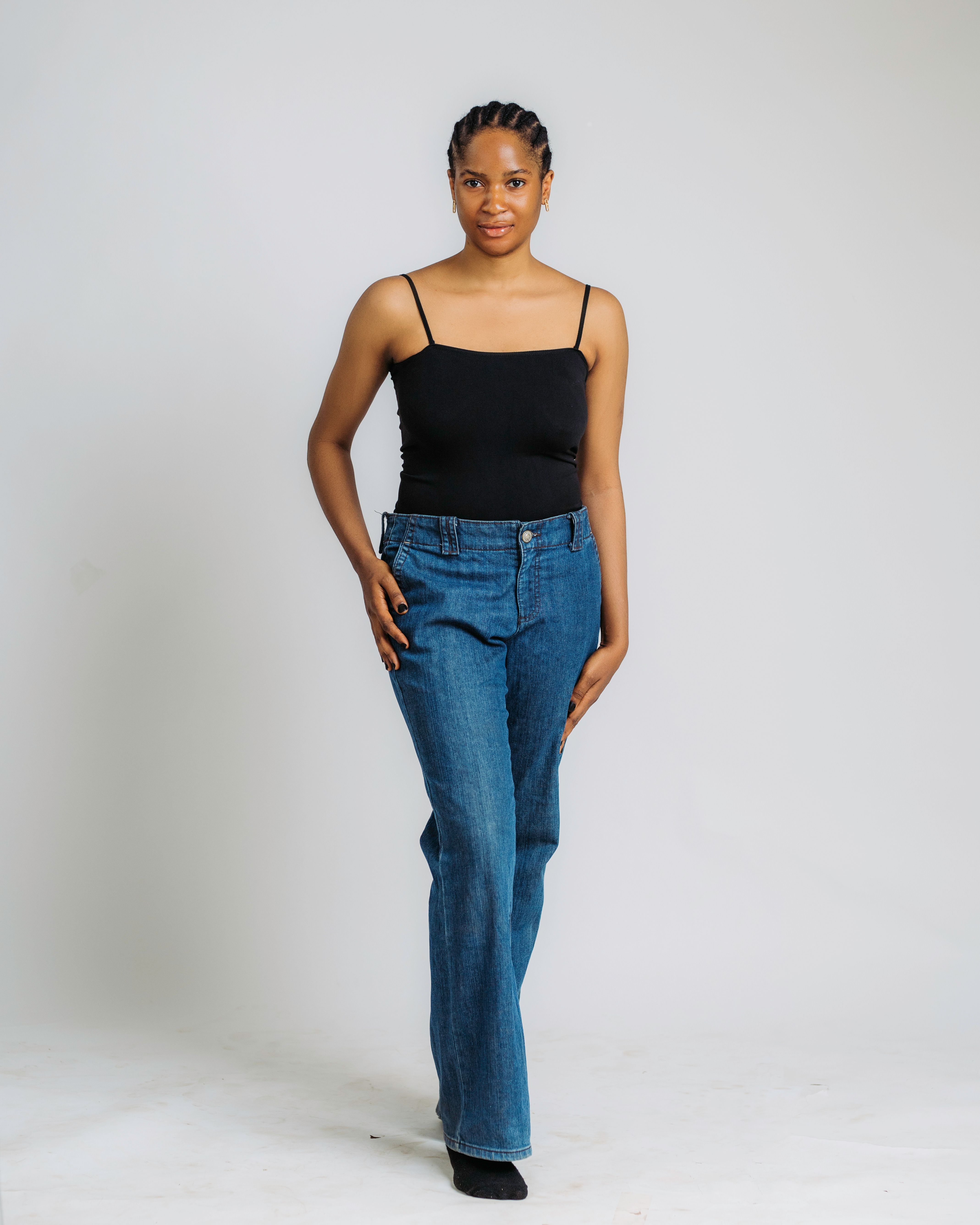 Portrait of a stylish woman wearing jeans and a black top against a neutral background.