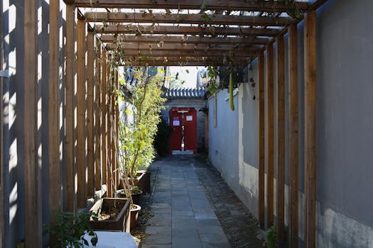 Uno stretto vicolo negli hutong di Pechino con porte rosse e tralicci di legno che proiettano ombre, simbolo dell'architettura tradizionale cinese.