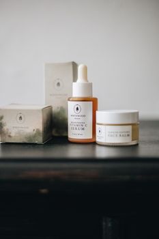 Flat lay of natural skincare products including serum and face balm on dark wood surface, minimalist style.