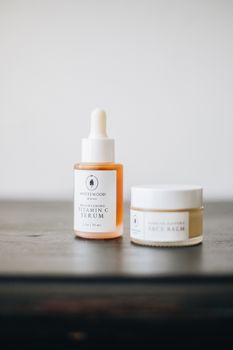 Minimalist flatlay of skincare serum and face balm with soft focus background.