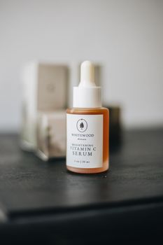 A minimalist aesthetic captures a Vitamin C serum dropper bottle on a dark surface, emphasizing clean beauty.