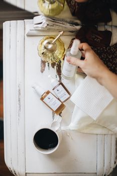 Top view of natural skincare products on a rustic white table with cozy decor.