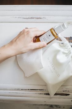 Hand holding a natural face oil with skincare items. Perfect for a minimalist skincare routine.