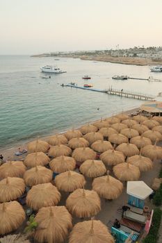 Idyllic tropical beach scene featuring straw umbrellas and boats in a serene coastal setting.