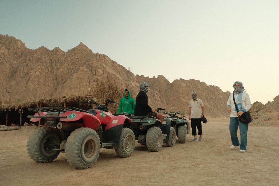 People on ATV excursion in desert, surrounded by rugged cliffs.