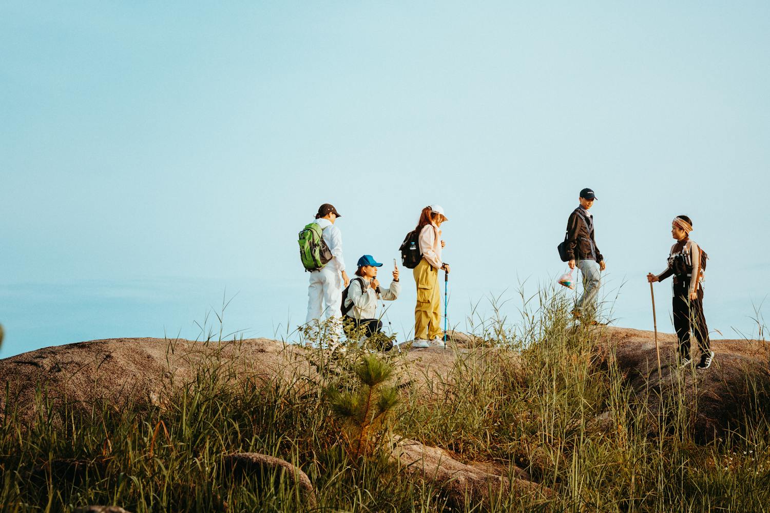 A group of young adults hiking in the outdoors of Kon Tum, Vietnam under a clear blue sky.