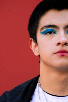 Close-up portrait featuring expressive blue eye makeup on a contrasting red background.