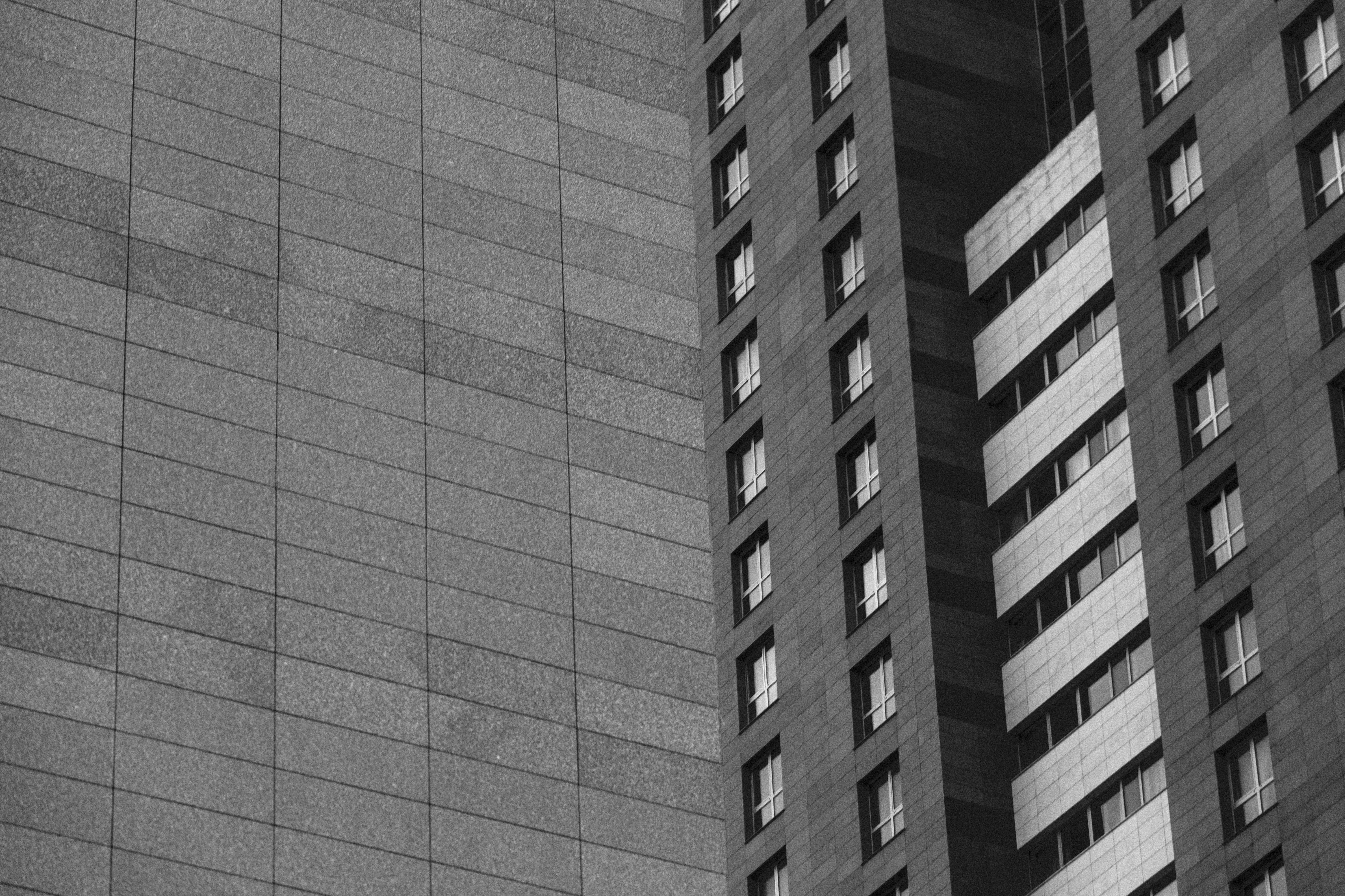 A monochrome photo capturing the sleek architecture of modern high-rise buildings with grid-like patterns.