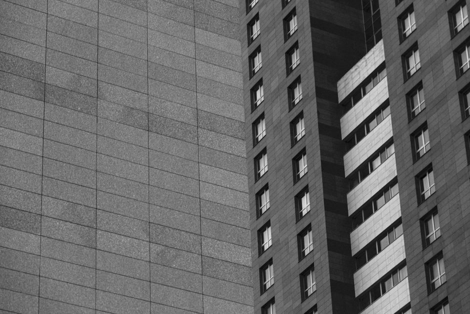 A monochrome photo capturing the sleek architecture of modern high-rise buildings with grid-like patterns.
