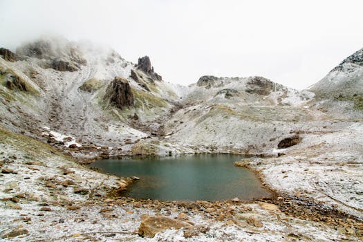 Serene snow-dusted mountain lake with rugged ridges and a tranquil atmosphere.